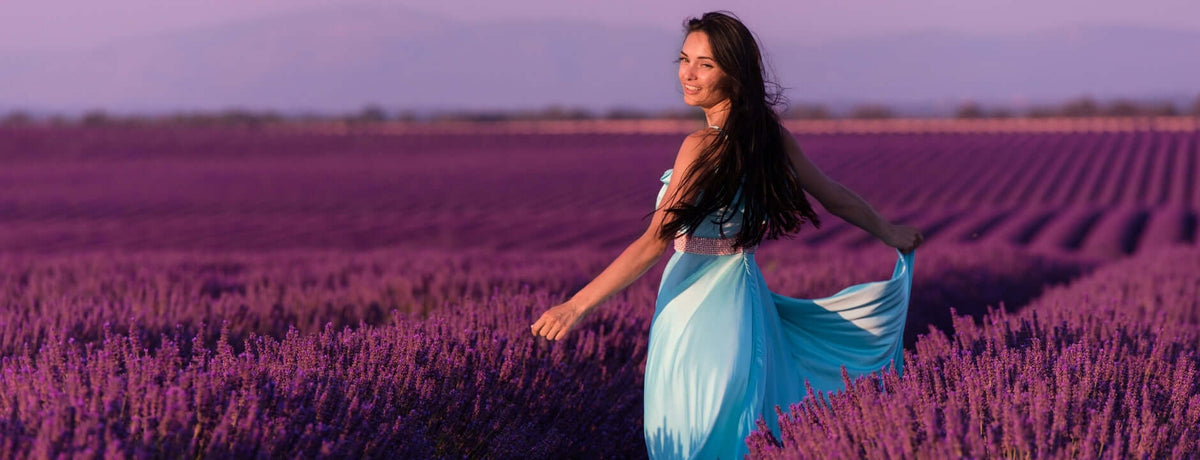 Woman in a blue dress standing in a lavender field with a blurred background
